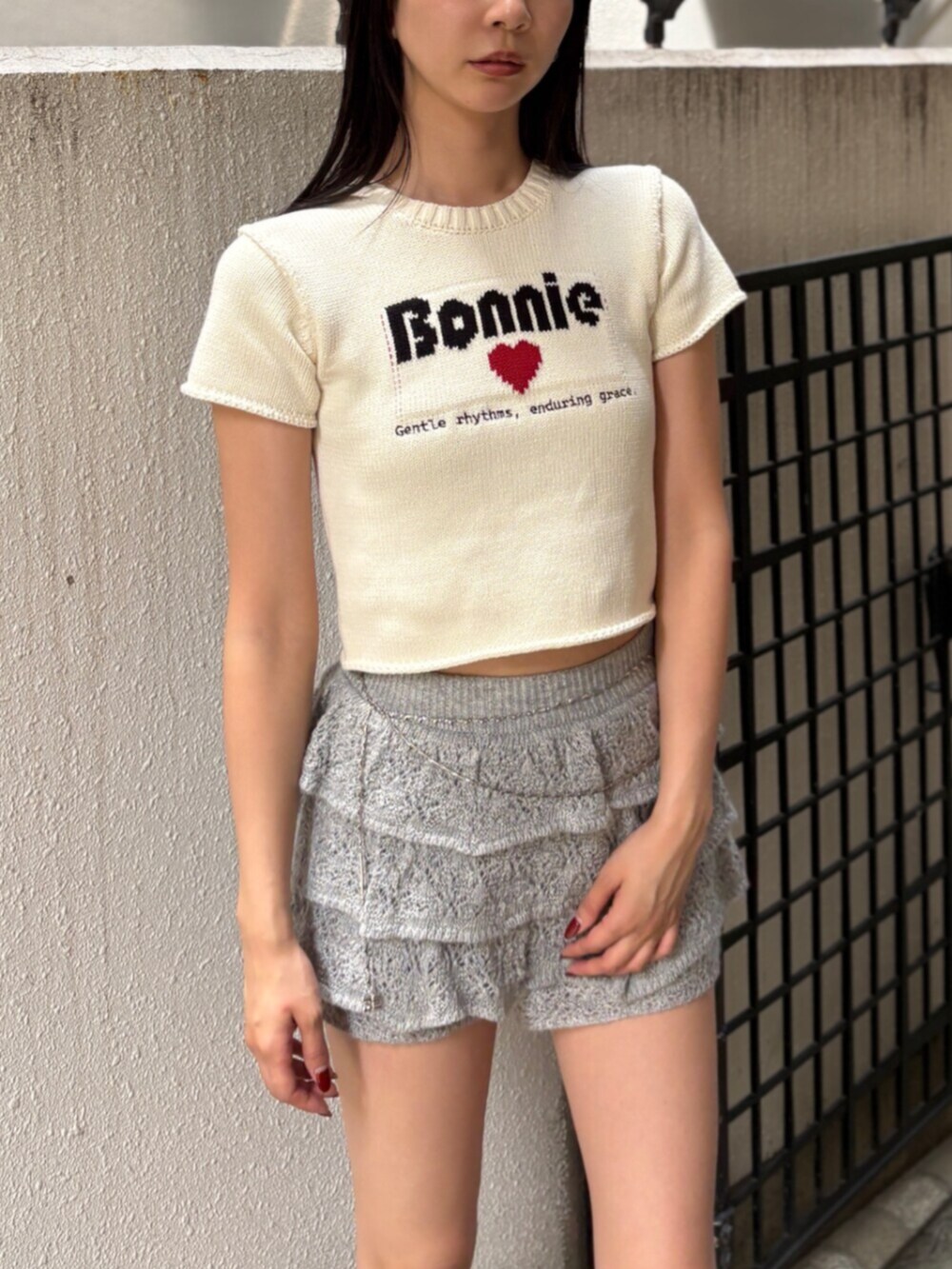 ブラック系のブーツ、ホワイト系のニット/セーター、グレー系のスカートを着用したレディースの夏コーディネートの5枚目の写真