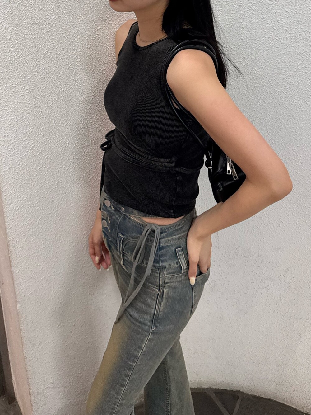 ブルー系のデニムパンツ、ブラック系のサンダル、ブラック系のハンドバッグを着用したレディースの夏コーディネートの2枚目の写真