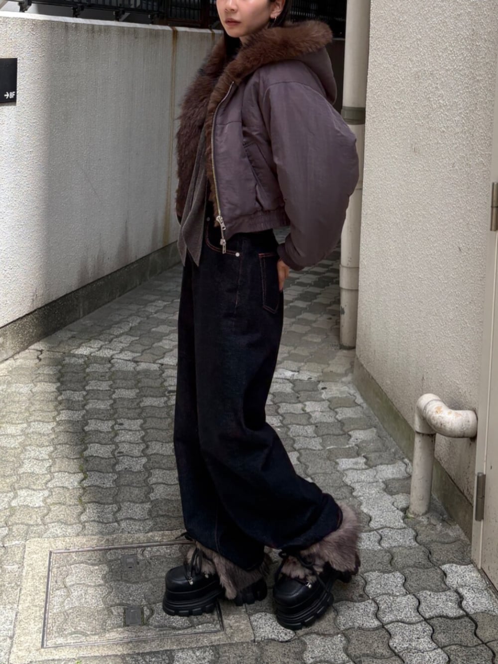 ブルー系のデニムパンツ、グレー系のブルゾン、ブラック系のブーツを着用したレディースの秋コーディネートの2枚目の写真
