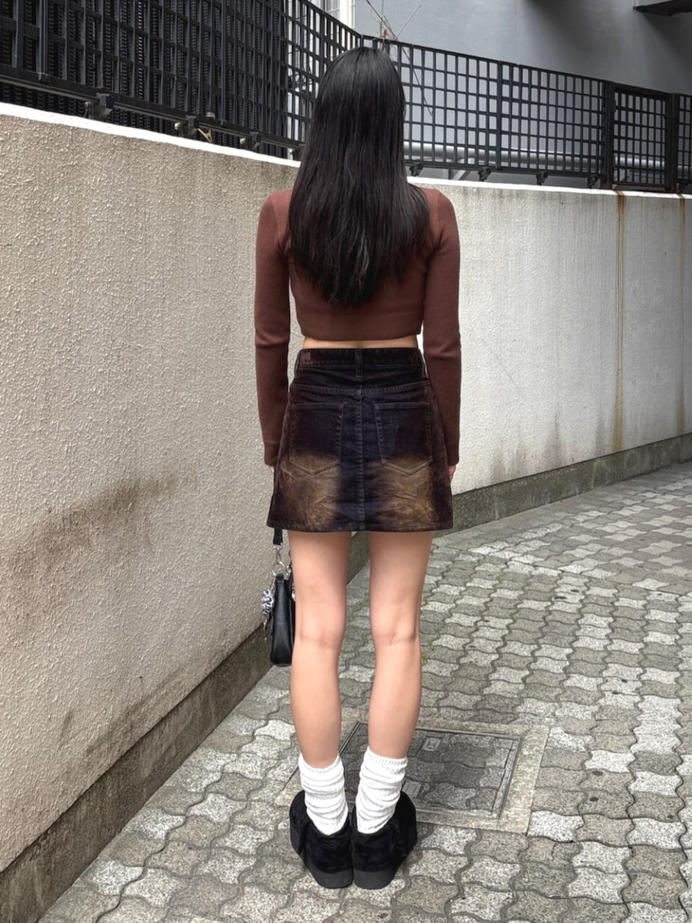ブラウン系のスカート、ブラック系のスリッポン、ブラウン系のニット/セーターを着用したレディースの夏コーディネートの3枚目の写真