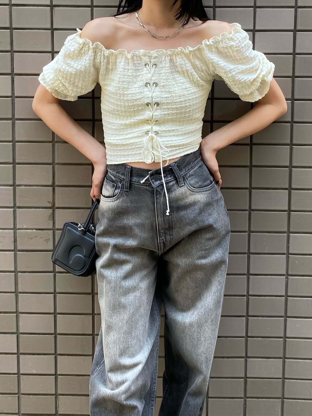 グレー系のデニムパンツ、ホワイト系のTシャツ/カットソー、ブラック系のハンドバッグを着用したレディースの夏コーディネートの2枚目の写真