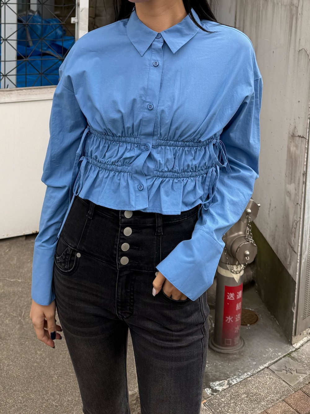 ブラック系のデニムパンツ、ブルー系のシャツ/ブラウス、ブラック系のスニーカーを着用したレディースの冬コーディネートの3枚目の写真