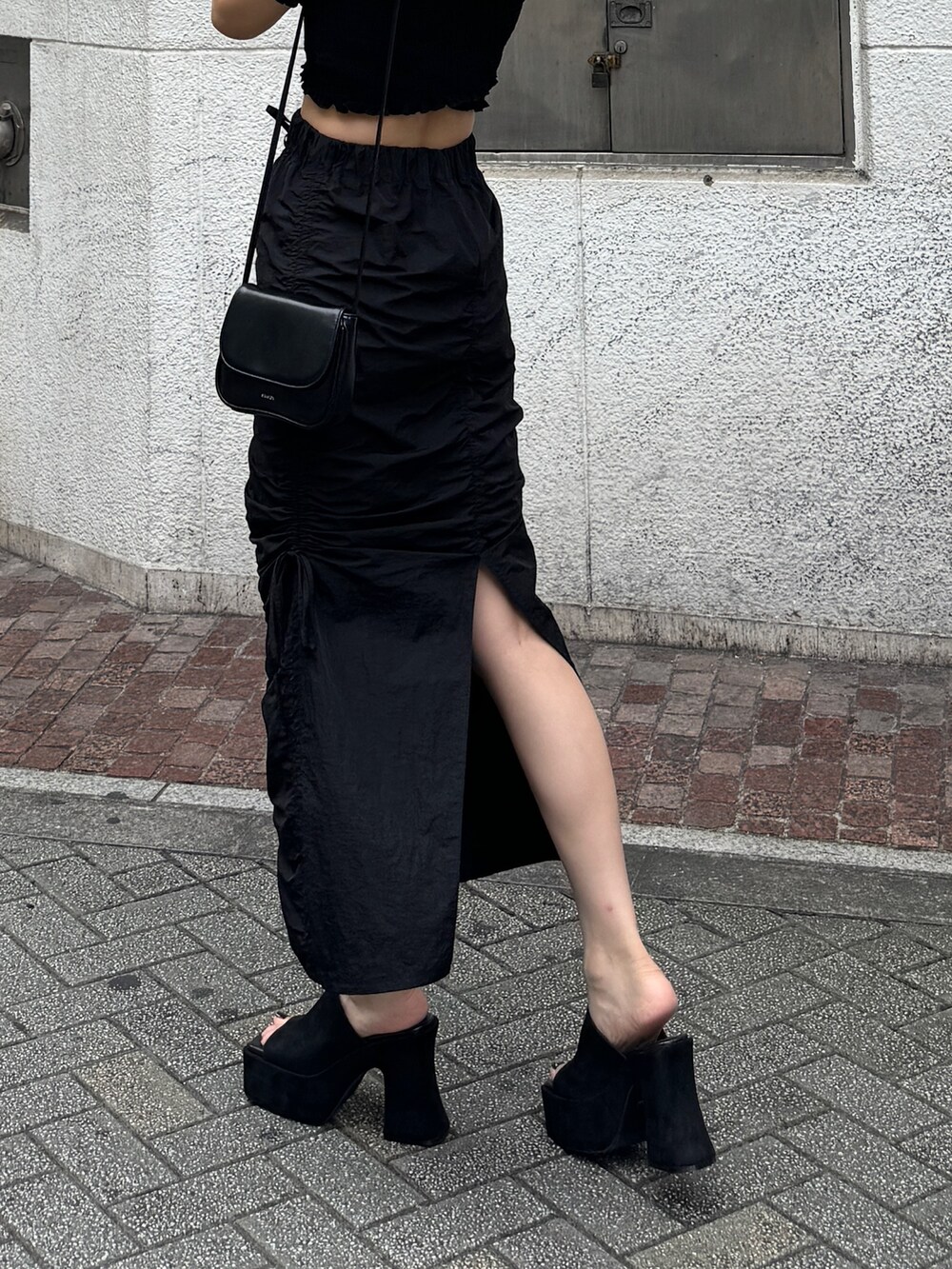 ブラック系のサンダル、ブラック系のスカート、ブラック系のTシャツ/カットソーを着用したレディースの夏コーディネートの2枚目の写真