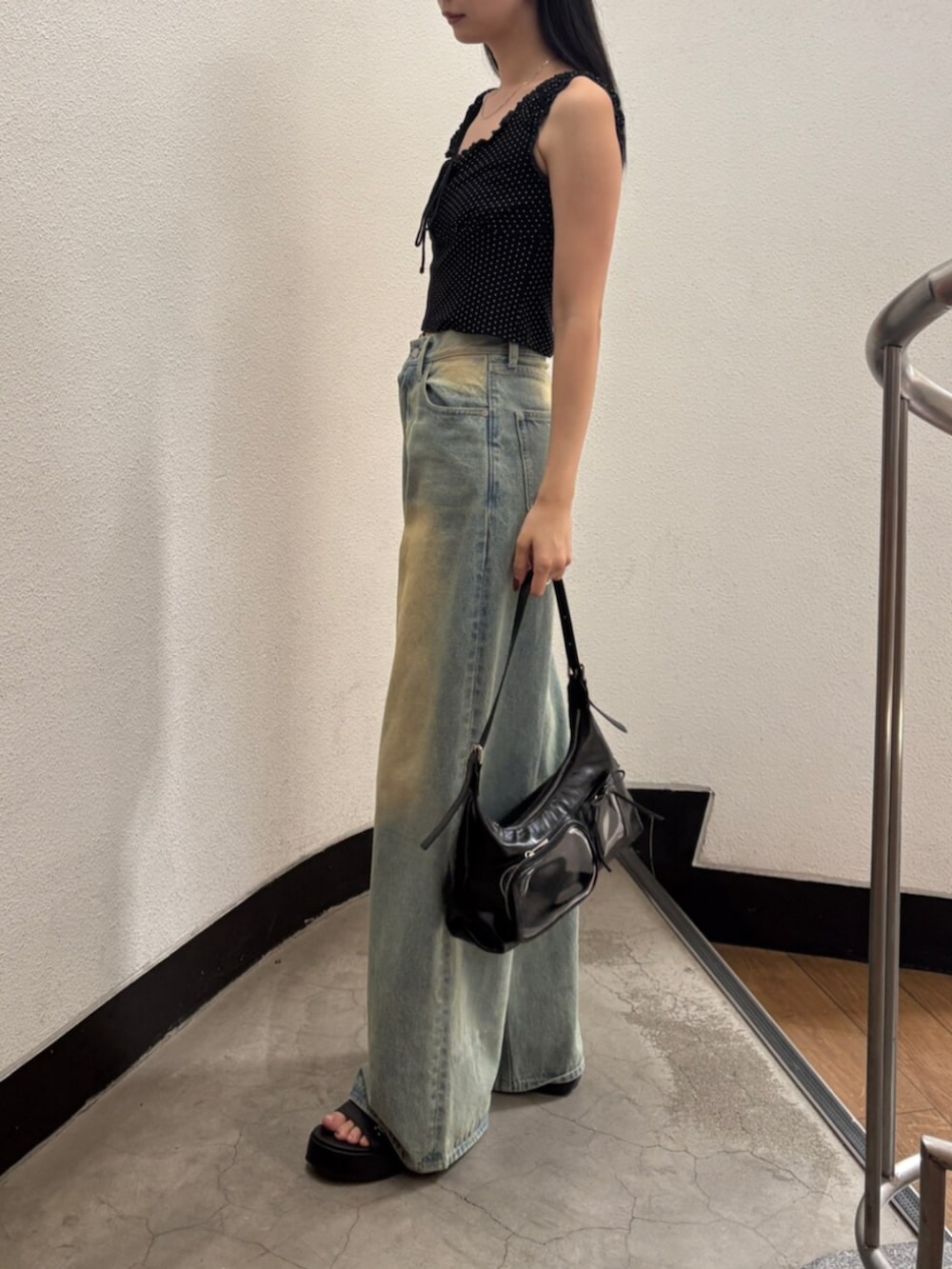 ブルー系のデニムパンツ、ブラック系のハンドバッグ、ブラック系のサンダルを着用したレディースの夏コーディネートの2枚目の写真