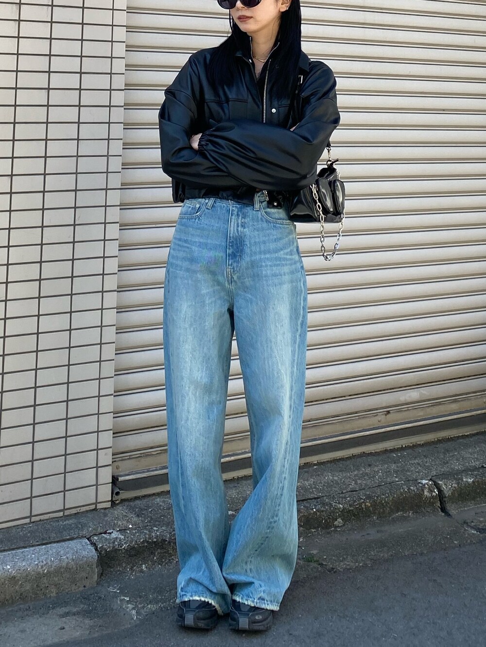 ブラック系のブルゾン、ブルー系のデニムパンツを着用したレディースの春コーディネートの3枚目の写真