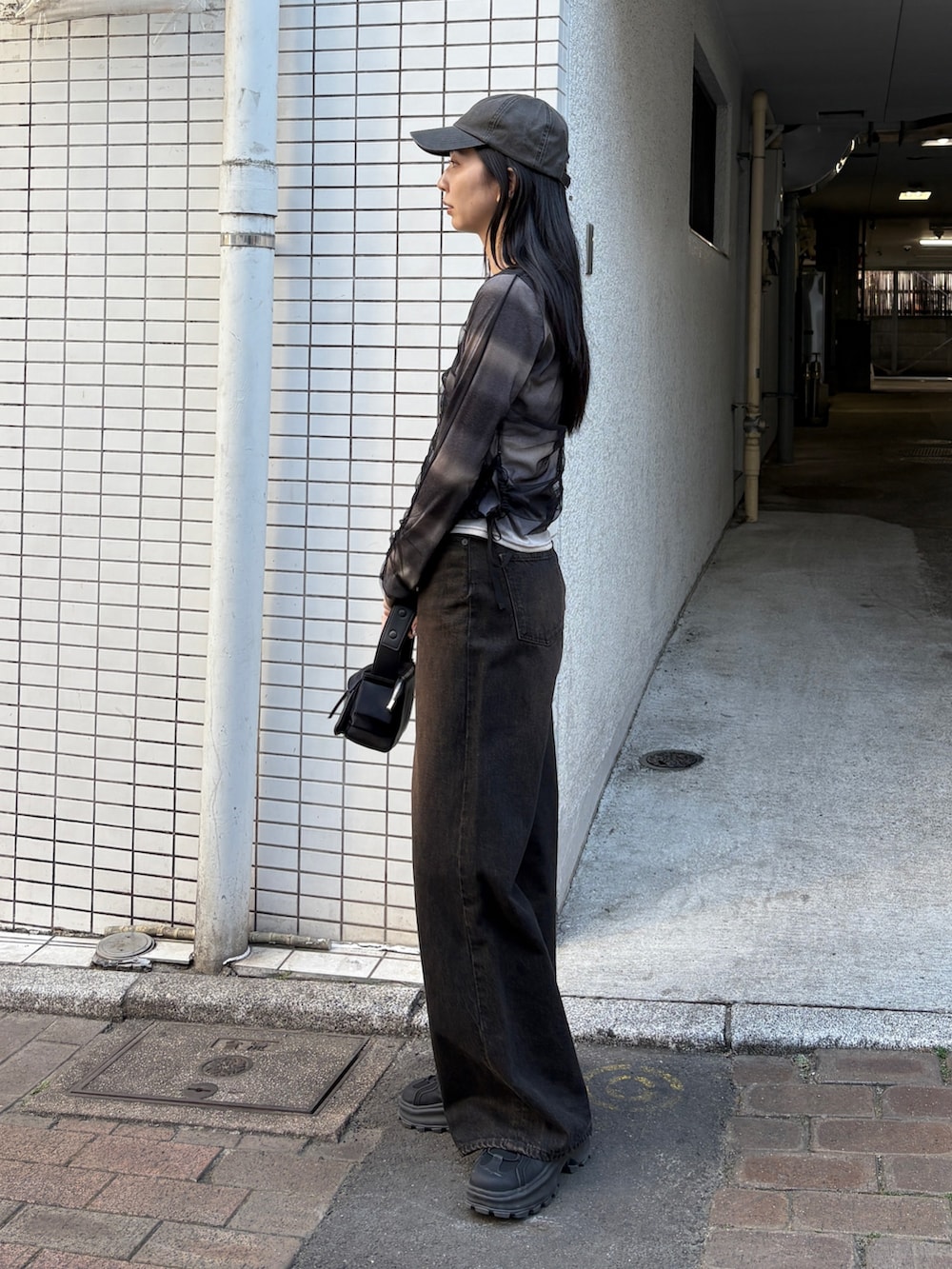 ブラック系のデニムパンツ、ブラック系のハンドバッグ、ブラック系のTシャツ/カットソーを着用したレディースの春コーディネートの2枚目の写真