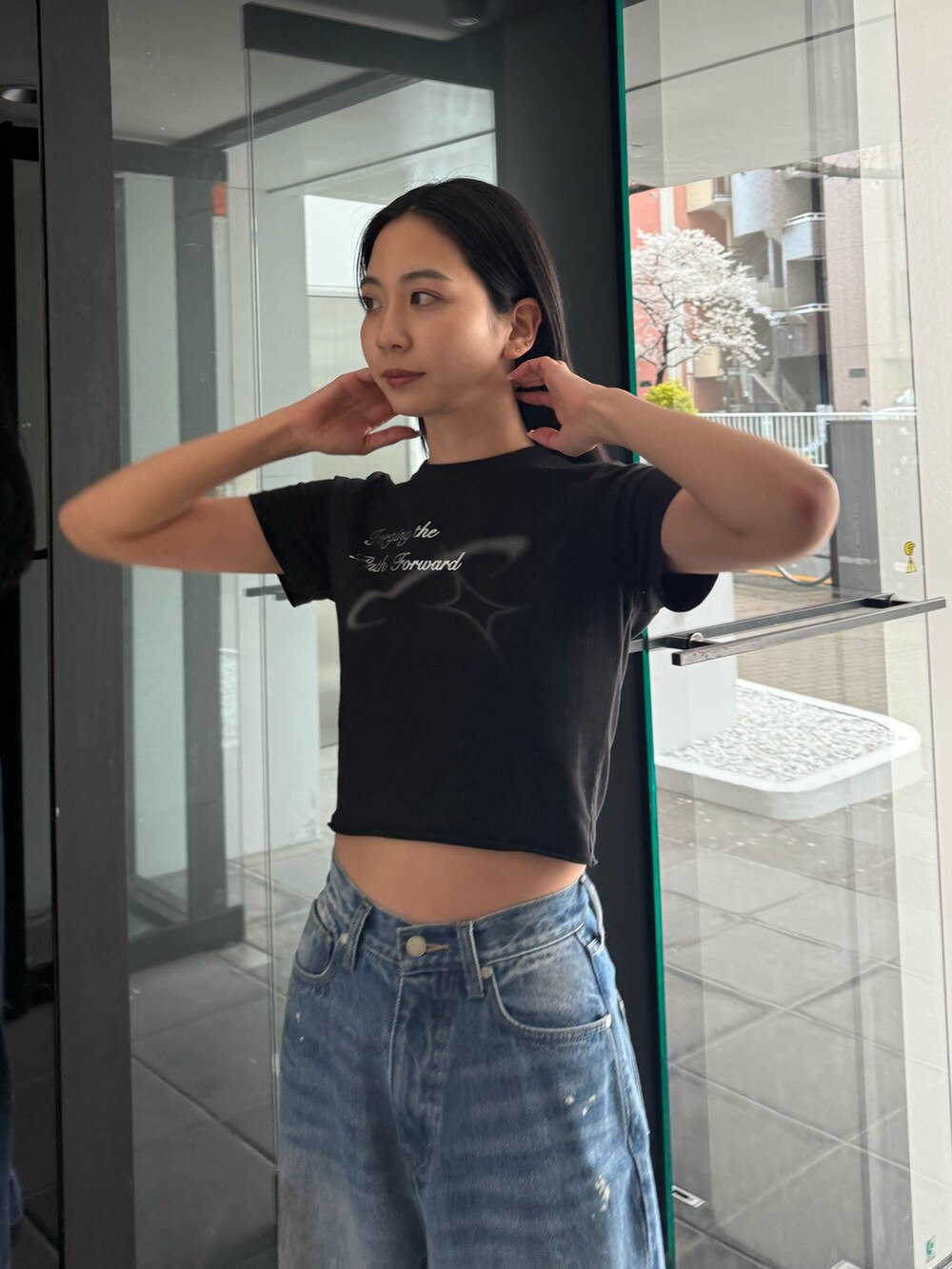 ブルー系のデニムパンツ、ブラック系のTシャツ/カットソー、ブラック系のサンダルを着用したレディースの春コーディネートの4枚目の写真