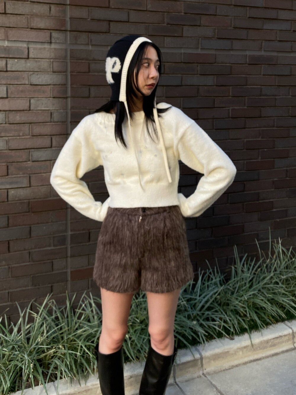 ホワイト系のニット/セーター、グレー系のその他パンツ、ブラック系のブーツを着用したレディースの冬コーディネートの2枚目の写真