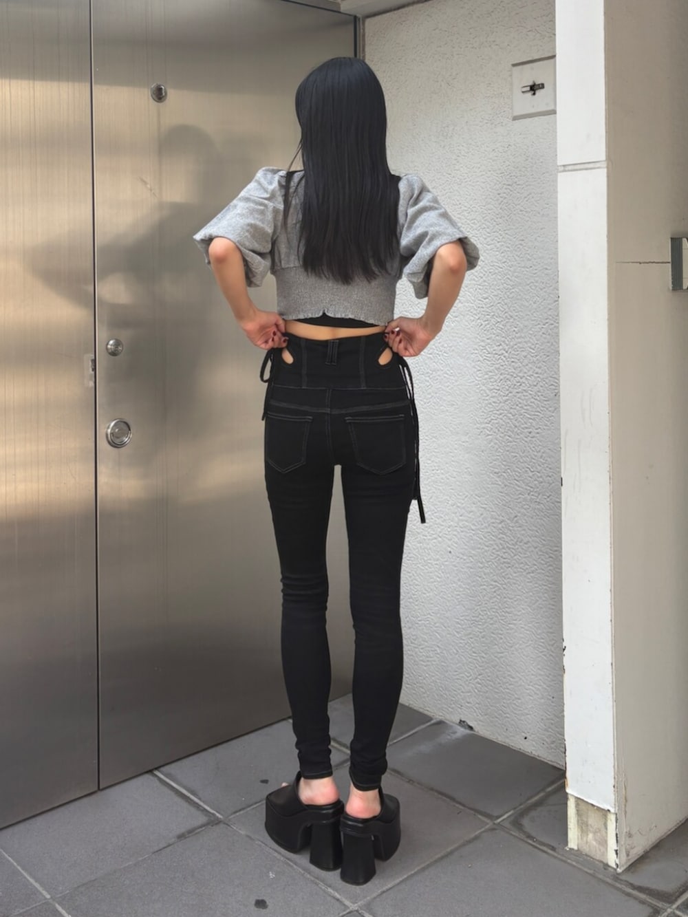 ブラック系のデニムパンツ、グレー系のTシャツ/カットソー、ブラック系のサンダルを着用したレディースの夏コーディネートの3枚目の写真
