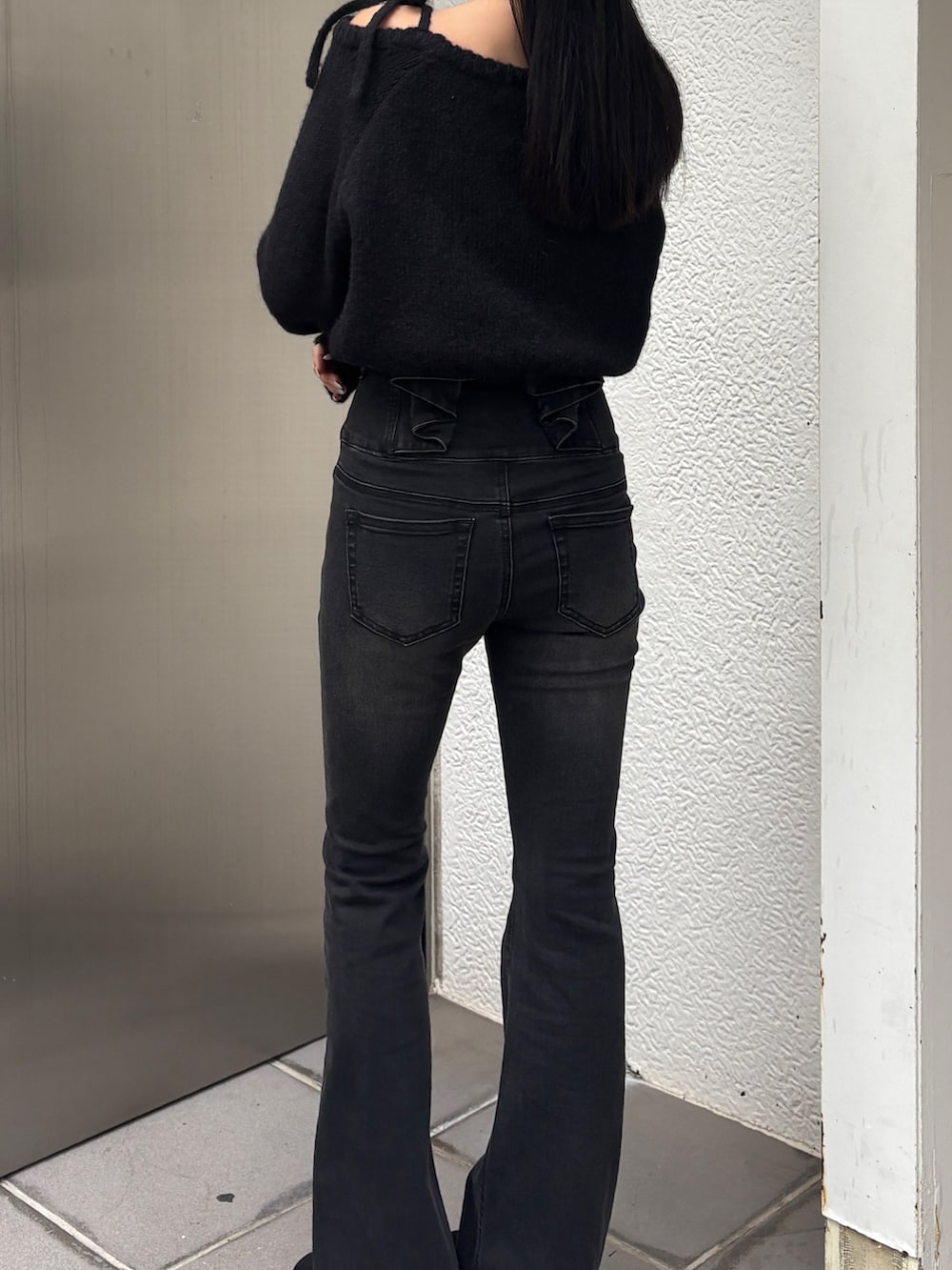 ブラック系のデニムパンツ、ブラック系のニット/セーター、ブラック系のブーツを着用したレディースの冬コーディネートの2枚目の写真