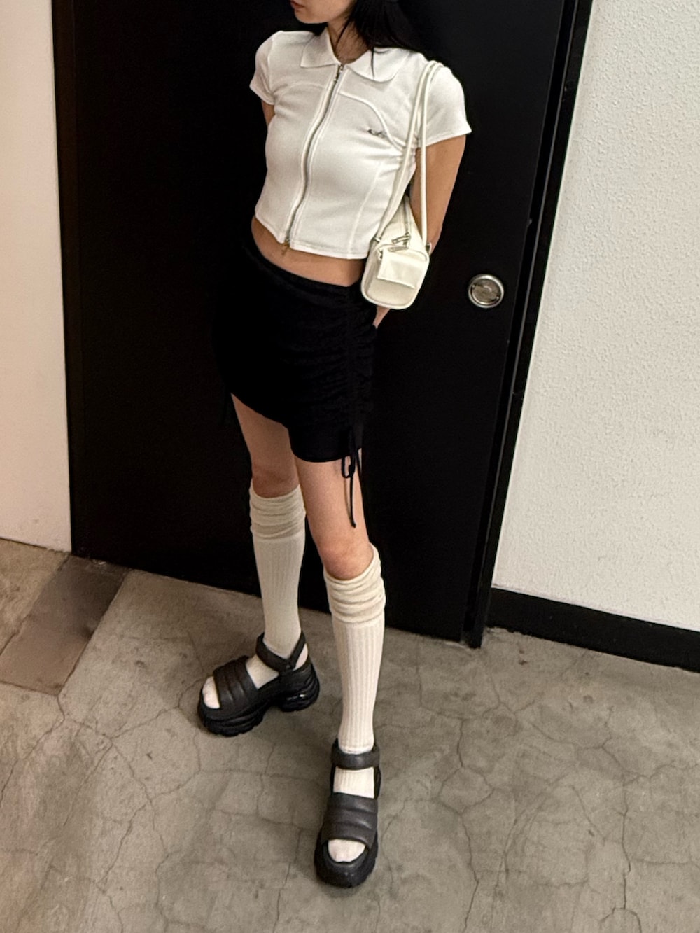 ブラック系のスカート、ホワイト系のTシャツ/カットソー、グレー系のサンダルを着用したレディースの夏コーディネートの4枚目の写真