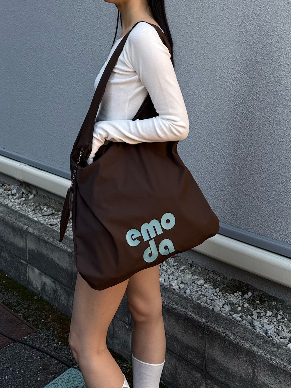 グレー系のスカート、ホワイト系のTシャツ/カットソー、ブラック系のスニーカーを着用したレディースの春コーディネートの2枚目の写真