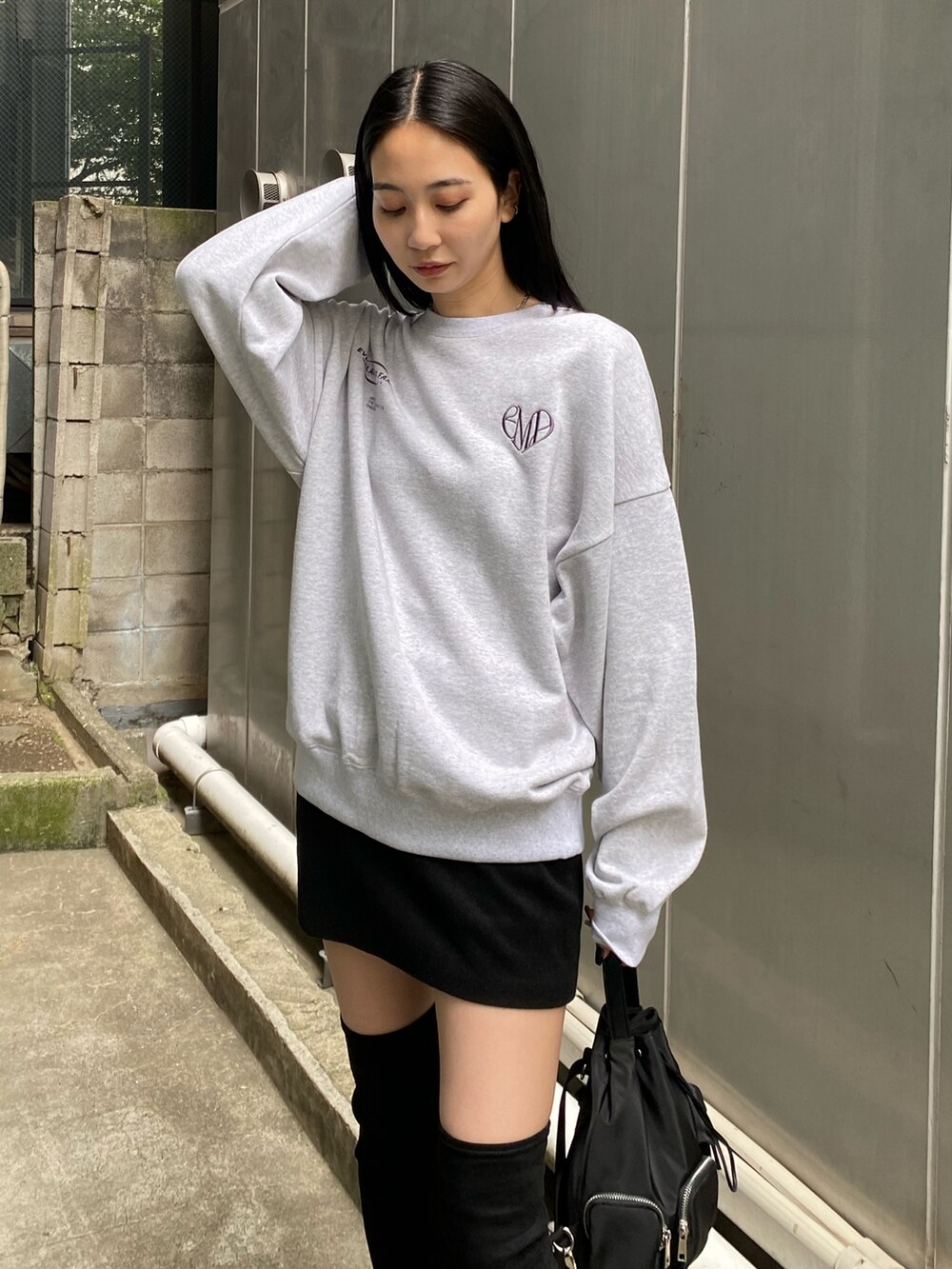 ブラック系のハンドバッグ、ブラック系のブーツ、グレー系のスウェットを着用したレディースの夏コーディネートの3枚目の写真