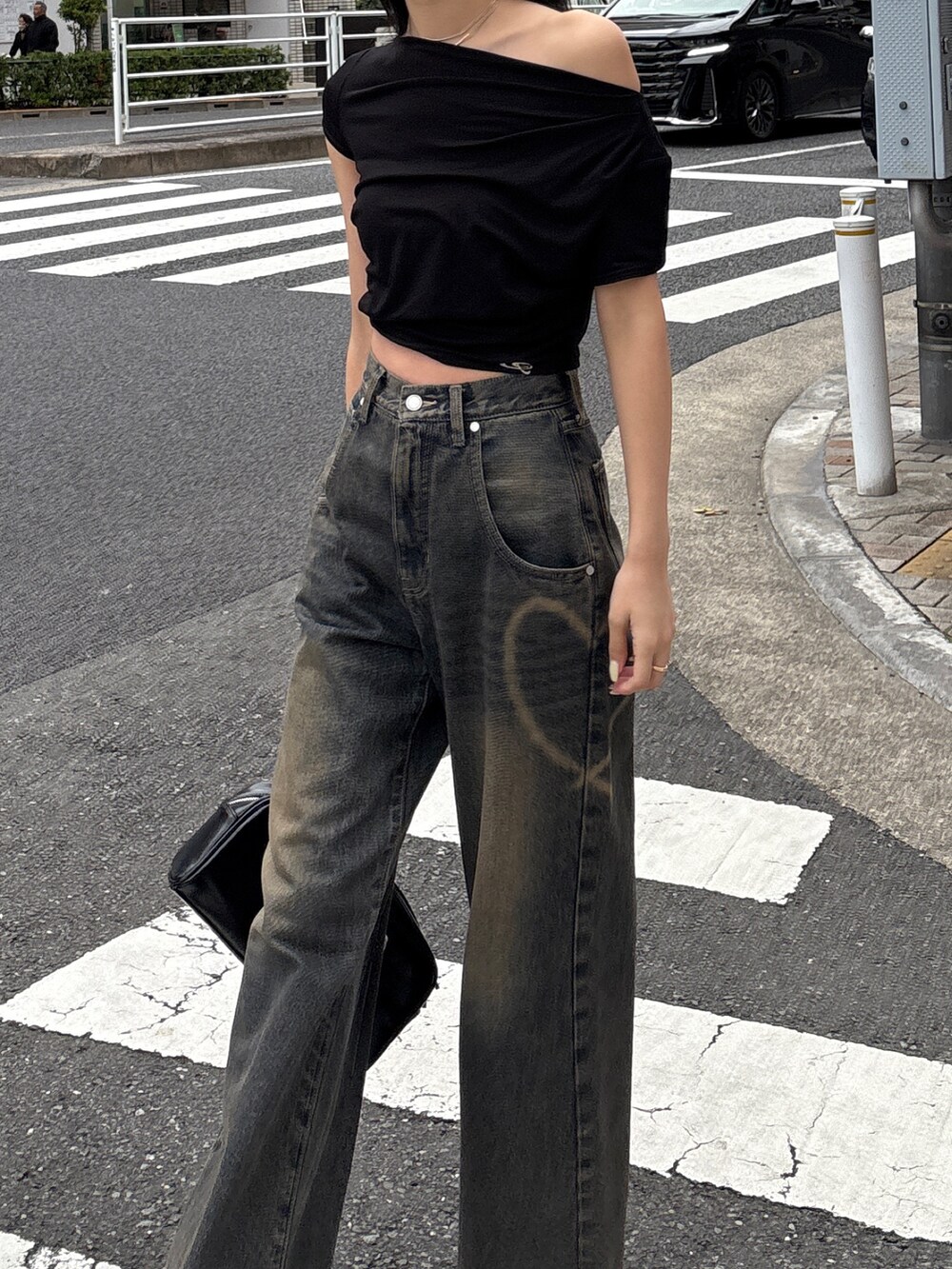 ブルー系のデニムパンツ、ブラック系のパンプス、ブラック系のハンドバッグを着用したレディースの夏コーディネートの3枚目の写真