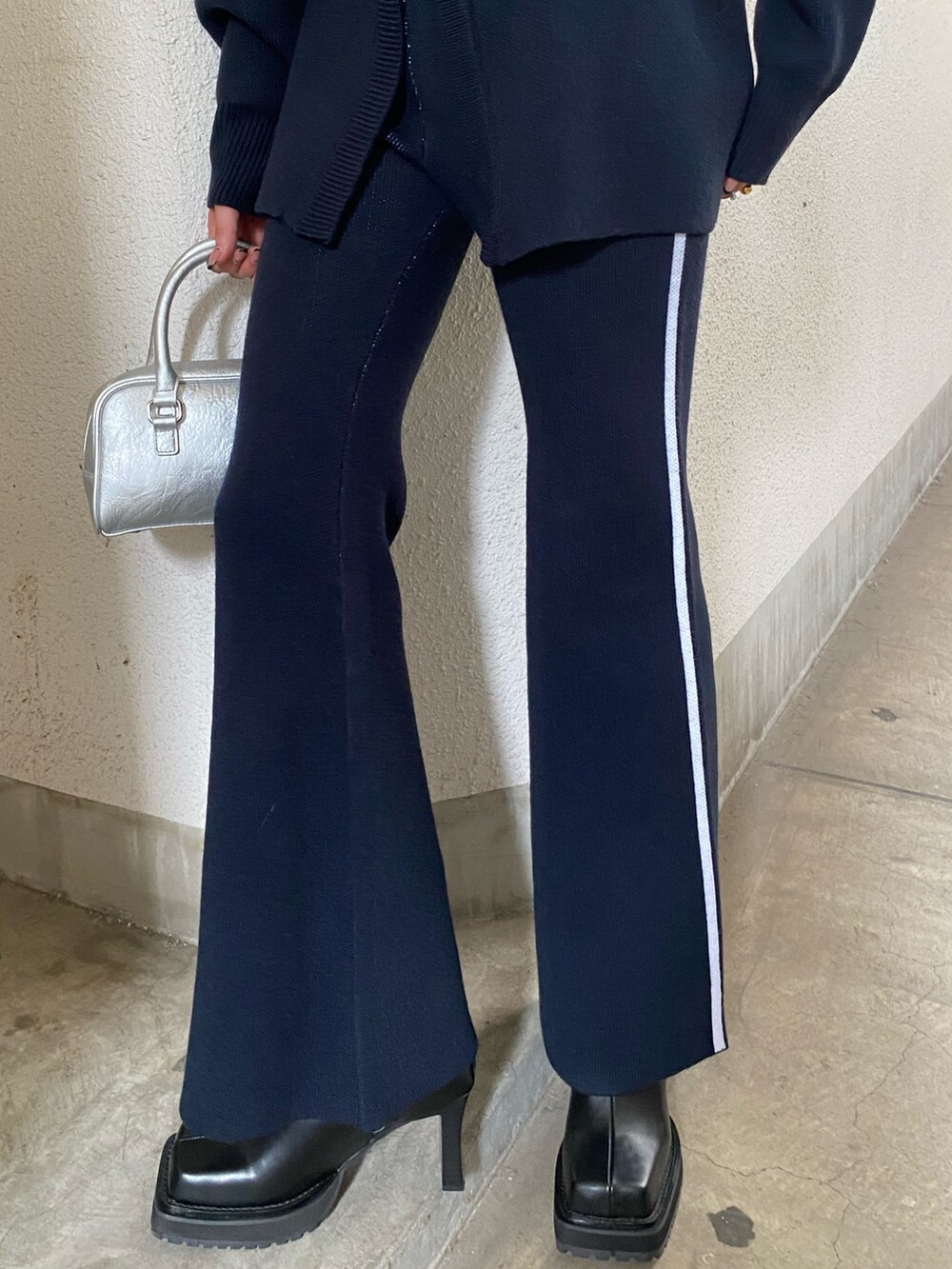 シルバー系のハンドバッグ、ブルー系のその他パンツ、ブラック系のブーツを着用したレディースの秋コーディネートの4枚目の写真