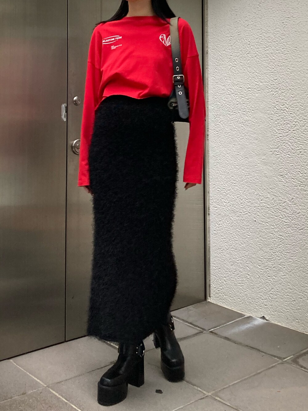 ブラック系のスカート、レッド系のTシャツ/カットソー、ブラック系のブーツを着用したレディースの秋コーディネートの2枚目の写真