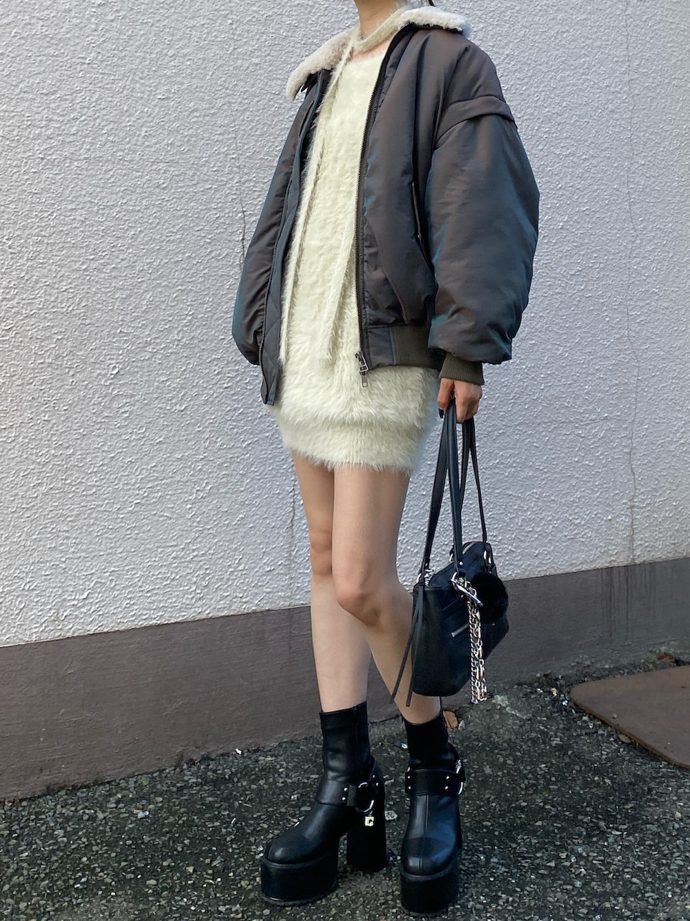 ホワイト系のワンピース、ブラック系のブーツ、ブラウン系のブルゾンを着用したレディースの秋コーディネートの2枚目の写真