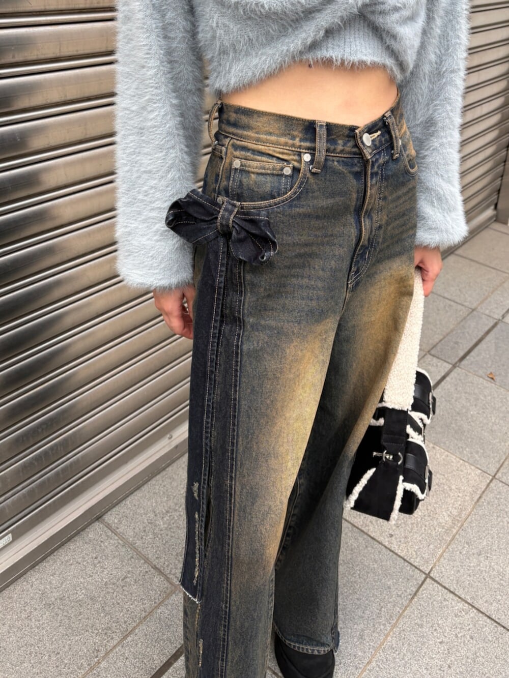 ブルー系のニット/セーター、ブルー系のデニムパンツ、ブラック系のハンドバッグを着用したレディースの秋コーディネートの5枚目の写真