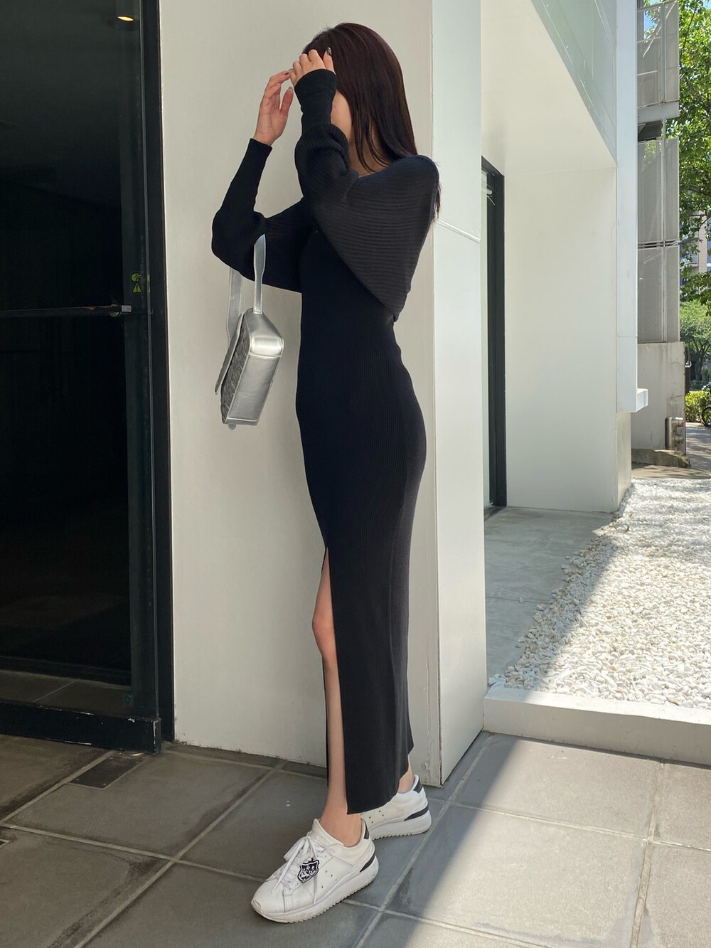 シルバー系のハンドバッグ、ブラック系のワンピースを着用したレディースの夏コーディネートの2枚目の写真