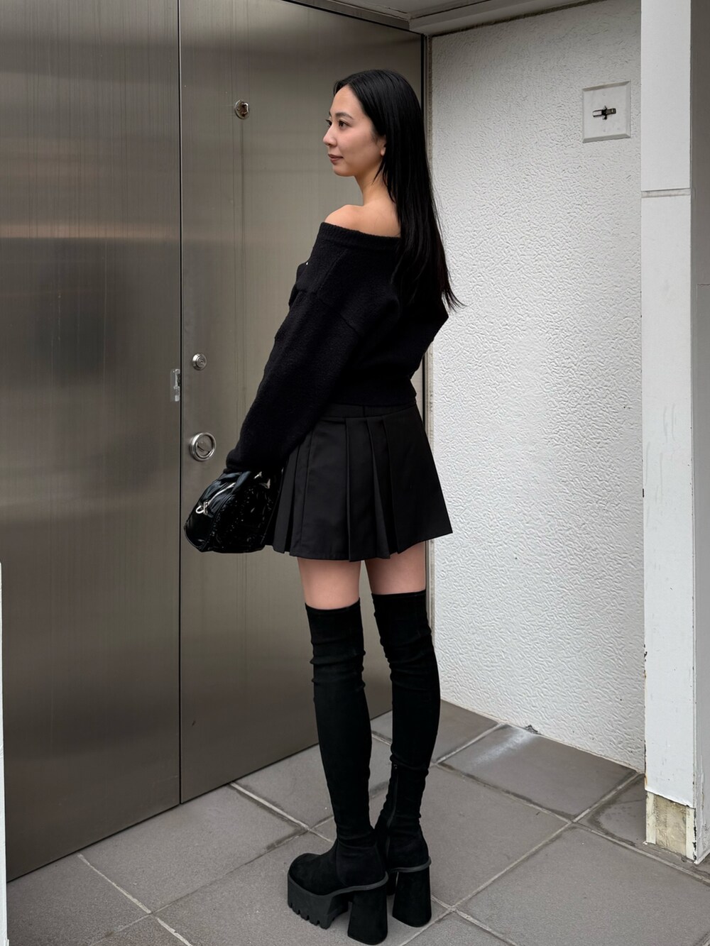 ブラック系のニット/セーター、ブラック系のスカート、ブラック系のブーツを着用したレディースの冬コーディネートの3枚目の写真