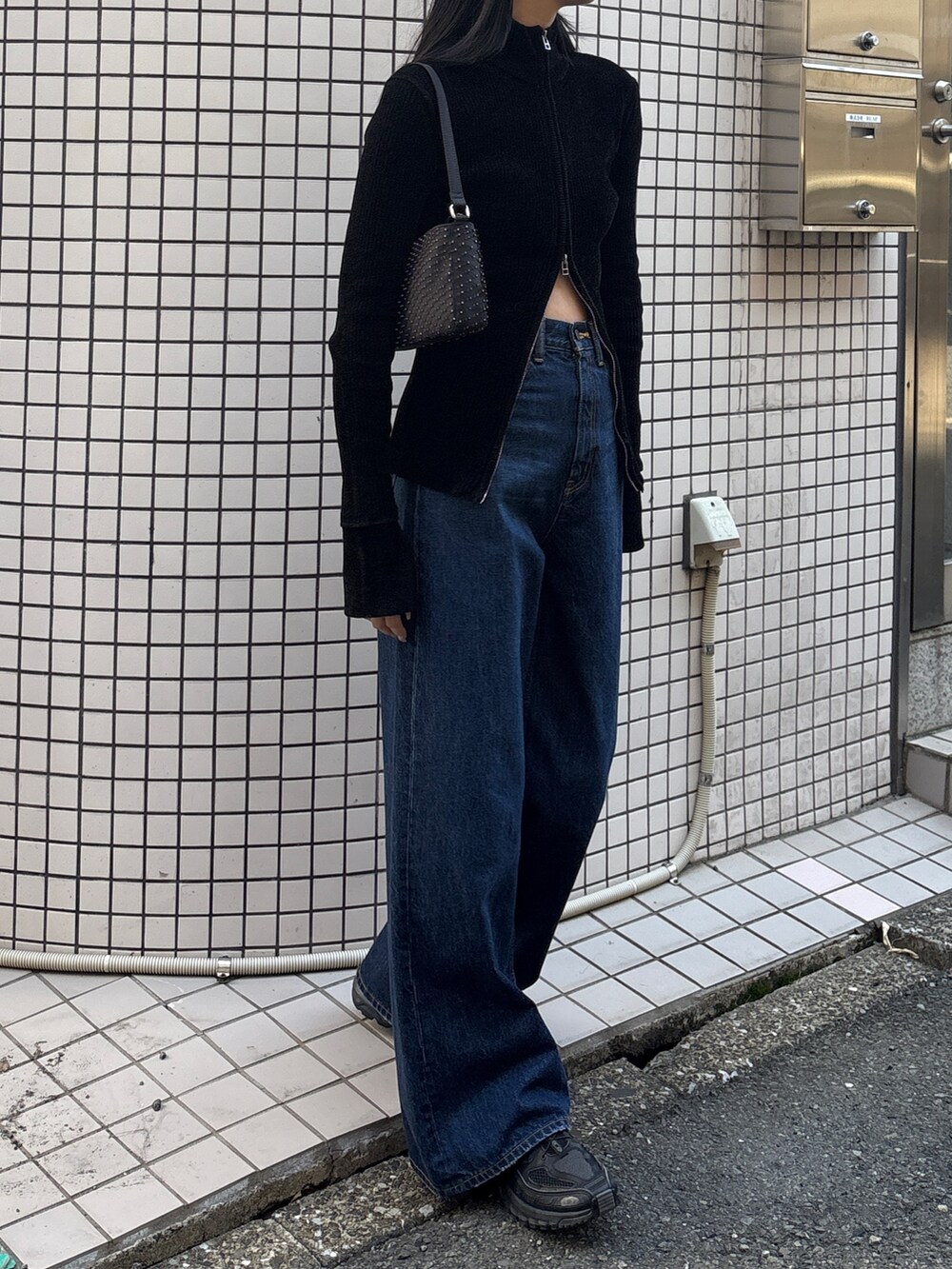 ブラック系のニット/セーター、ブルー系のデニムパンツを着用したレディースの秋コーディネートの2枚目の写真