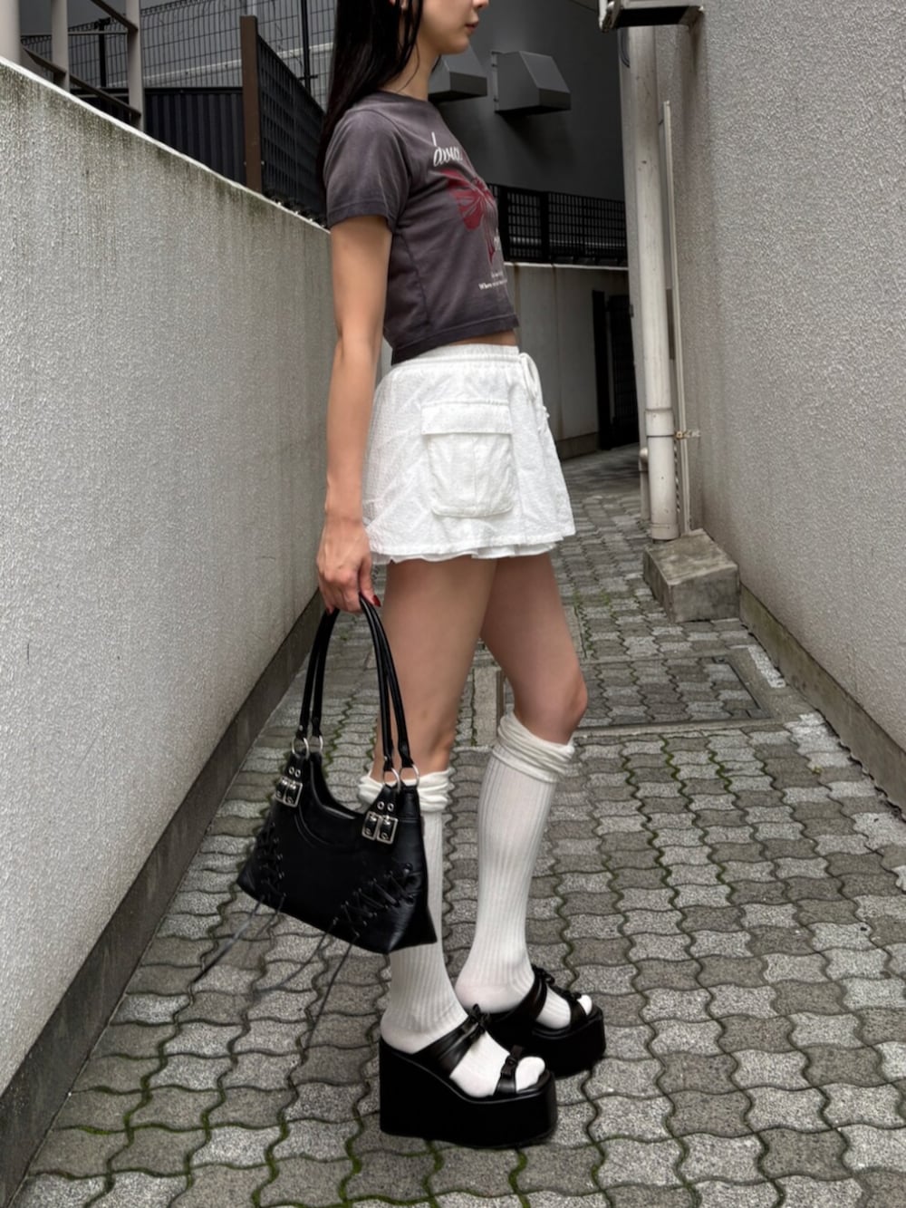 ブラック系のショルダーバッグ、ブラック系のサンダル、ブラック系のTシャツ/カットソーを着用したレディースの夏コーディネートの2枚目の写真