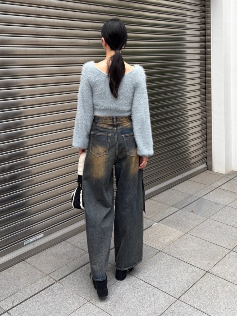 ブルー系のニット/セーター、ブルー系のデニムパンツ、ブラック系のハンドバッグを着用したレディースの秋コーディネートの3枚目の写真