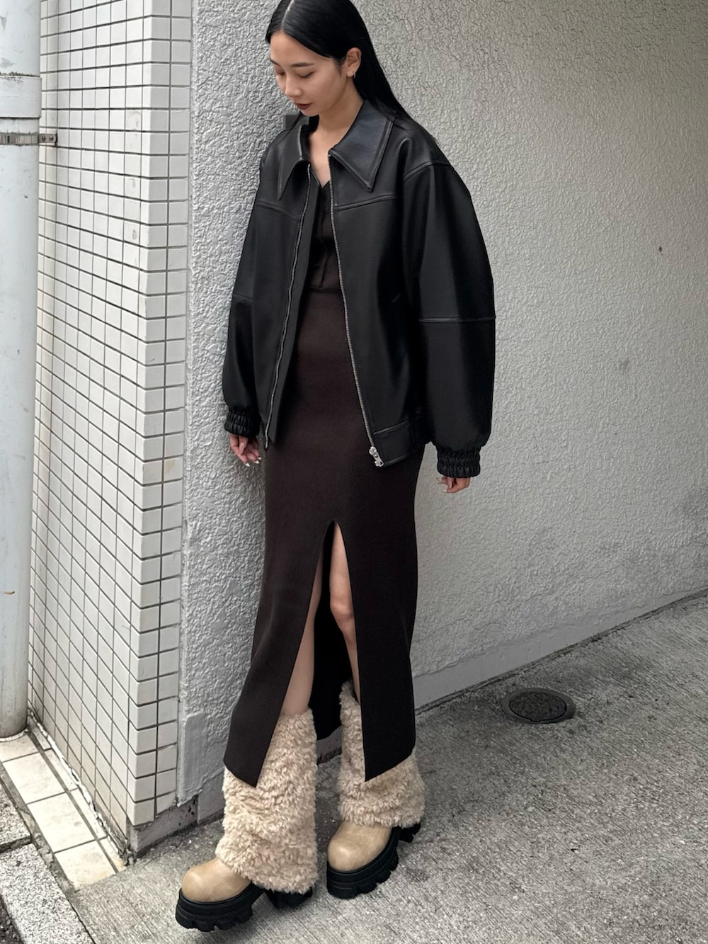 ブラック系のブルゾン、ブラウン系のワンピース、ホワイト系のブーツを着用したレディースの冬コーディネートの3枚目の写真