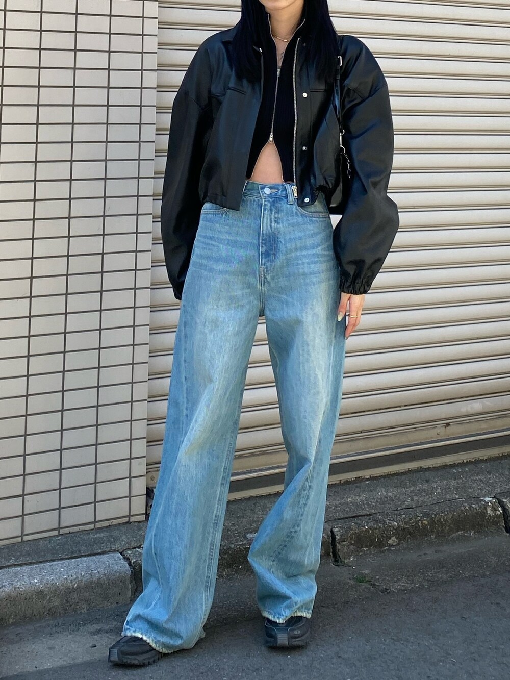 ブラック系のブルゾン、ブルー系のデニムパンツを着用したレディースの春コーディネートの2枚目の写真