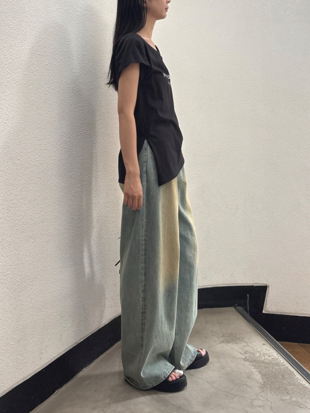 ブルー系のデニムパンツ、ブラック系のハンドバッグ、ブラック系のTシャツ/カットソーを着用したレディースの夏コーディネートの2枚目の写真