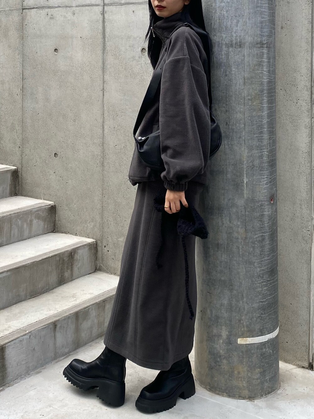 グレー系のスカート、ブラック系のショルダーバッグ、グレー系のTシャツ/カットソーを着用したレディースの秋コーディネートの2枚目の写真