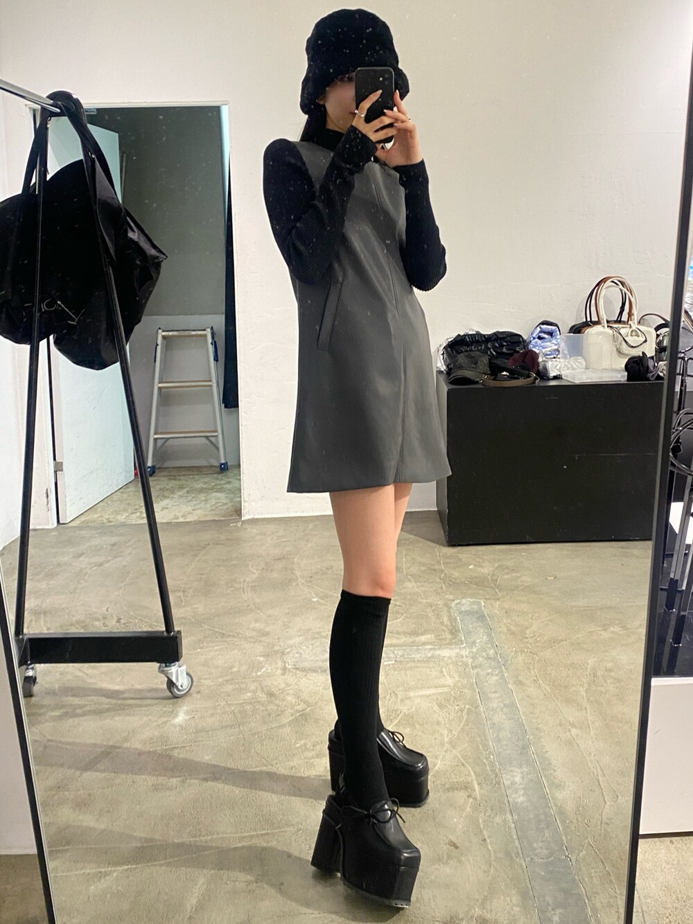 グレー系のワンピース、ブラック系のニット/セーター、ブラック系のサンダルを着用したレディースの秋コーディネートの4枚目の写真