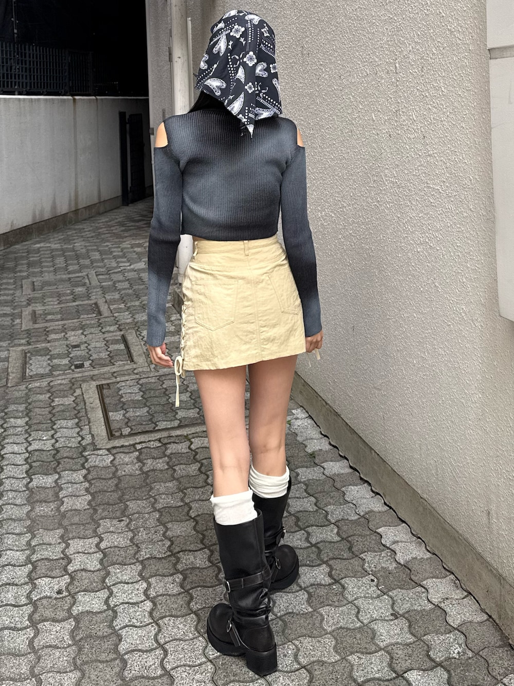 ブラック系のブーツ、イエロー系のスカート、ブラック系のニット/セーターを着用したレディースの春コーディネートの2枚目の写真
