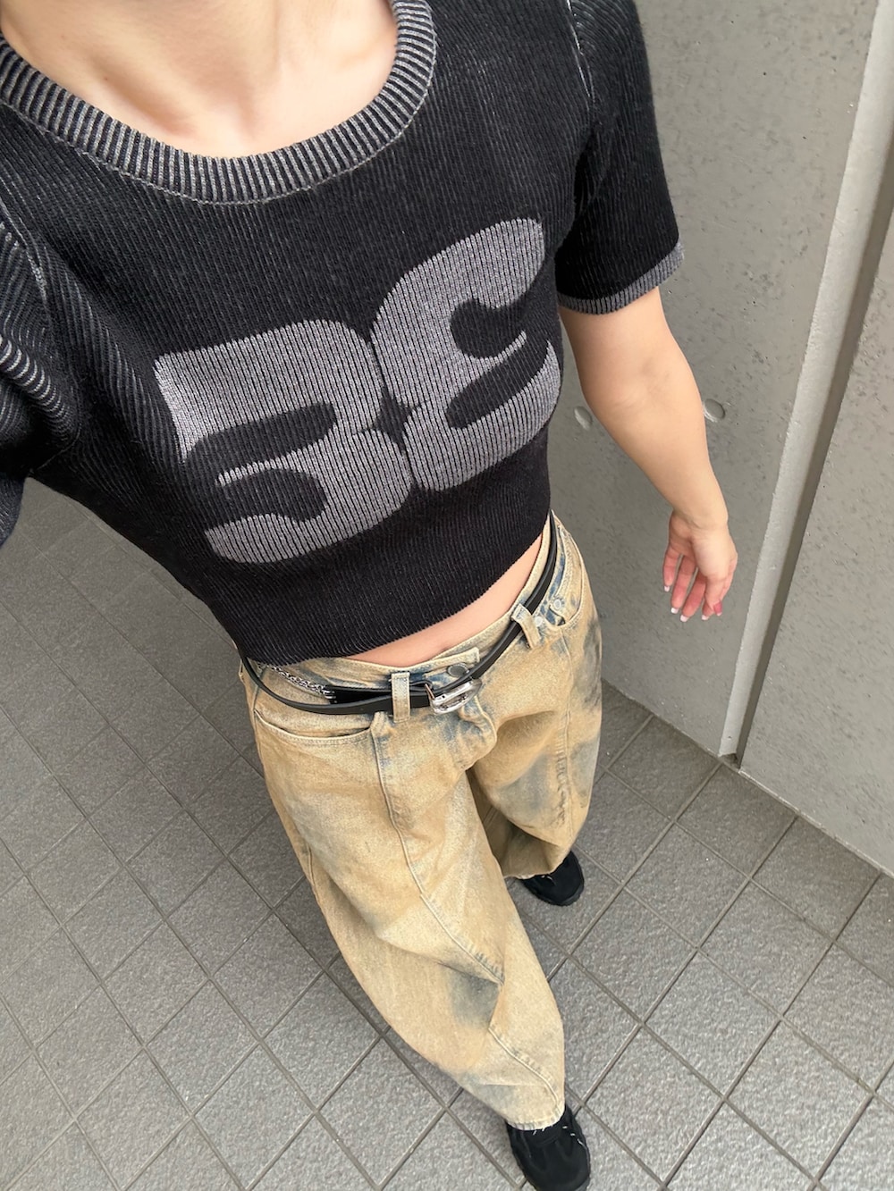 ベージュ系のデニムパンツ、ブラック系のニット/セーター、ブラック系のスニーカーを着用したレディースの夏コーディネートの3枚目の写真