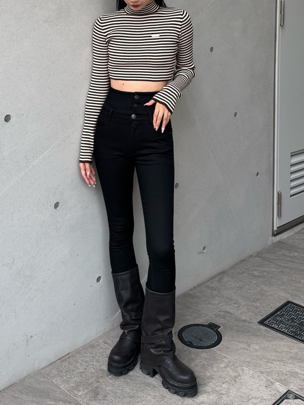 ブラック系のデニムパンツ、ブラウン系のニット/セーター、ブラック系のブーツを着用したレディースの冬コーディネートの2枚目の写真