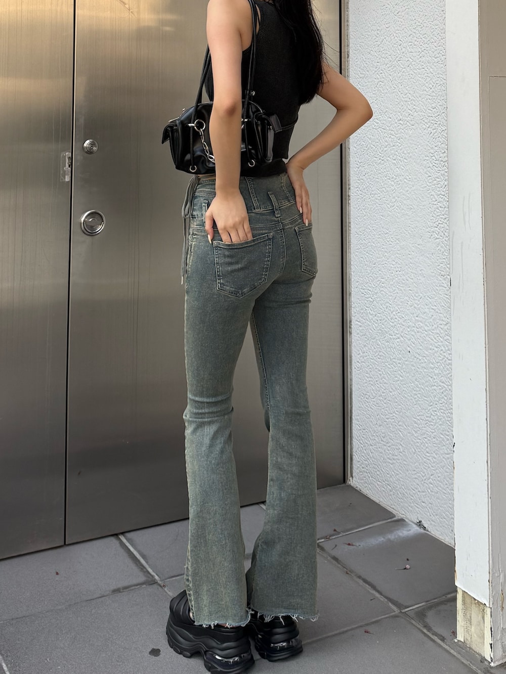 ブルー系のデニムパンツ、ブラック系のサンダル、ブラック系のハンドバッグを着用したレディースの夏コーディネートの4枚目の写真