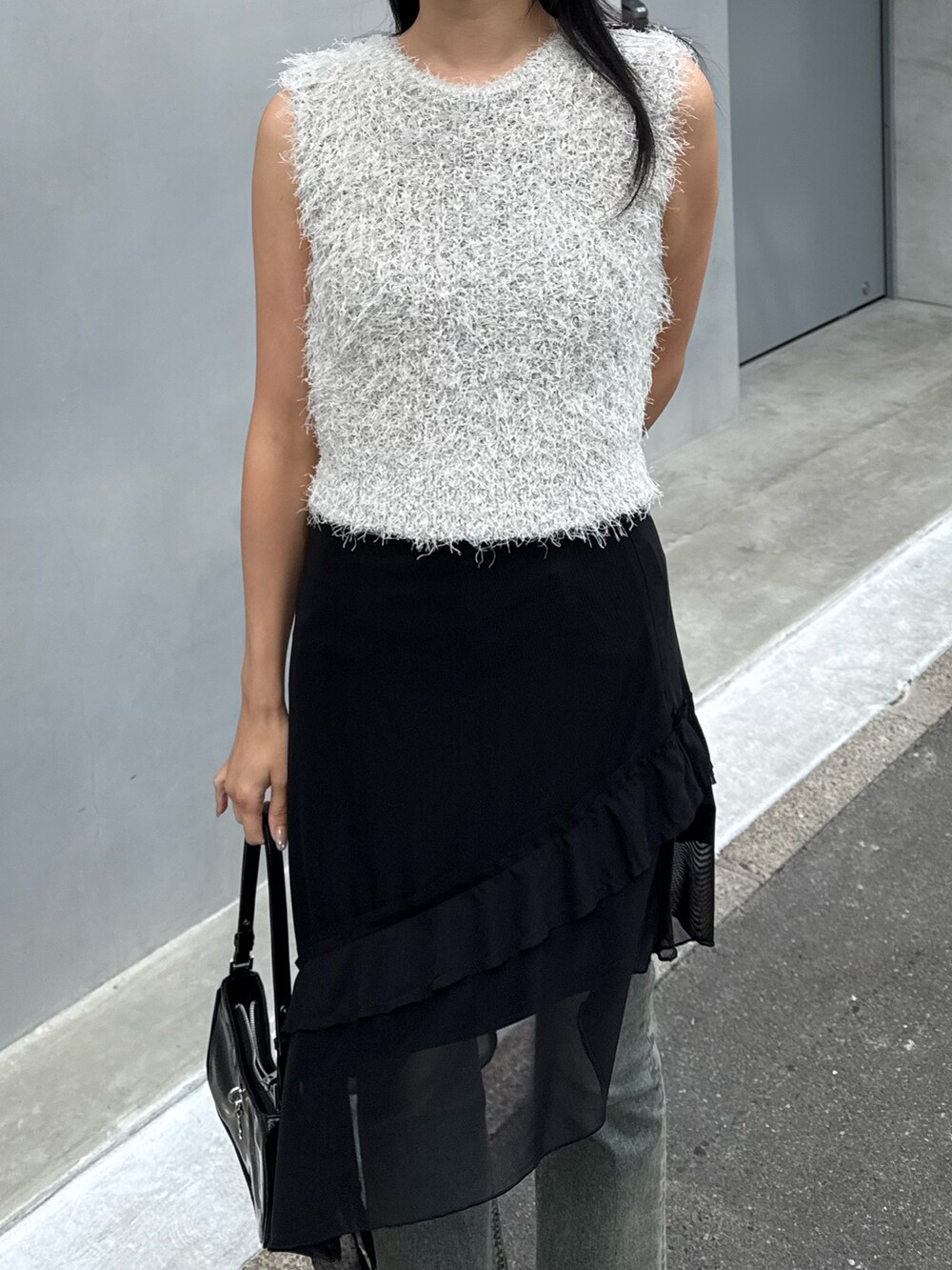 ブラック系のスカート、ブルー系のデニムパンツ、ブラック系のパンプスを着用したレディースの春コーディネートの3枚目の写真