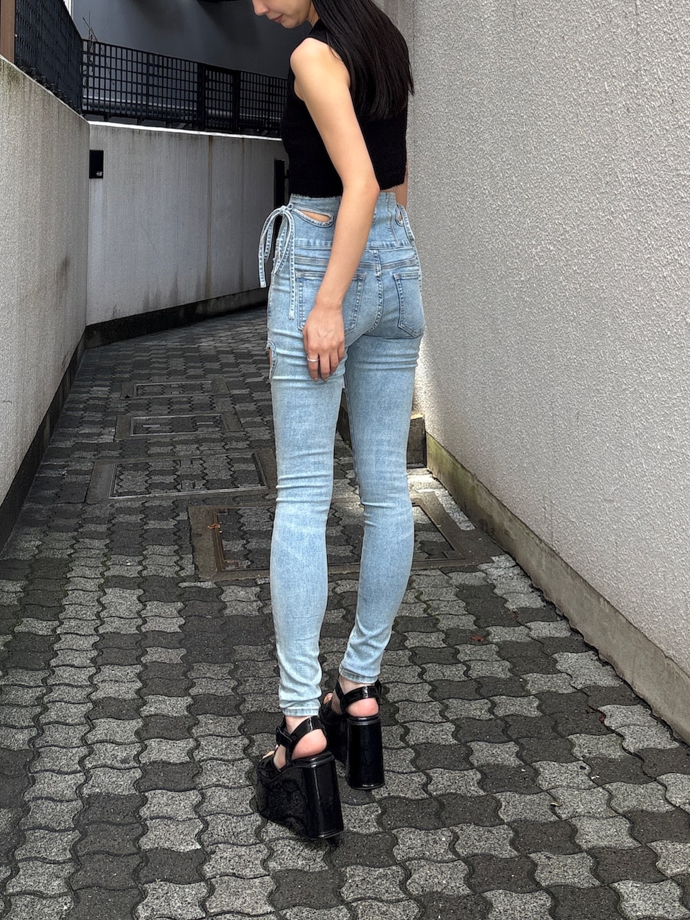 ブルー系のデニムパンツ、ブラック系のニット/セーター、ブラック系のサンダルを着用したレディースの夏コーディネートの4枚目の写真