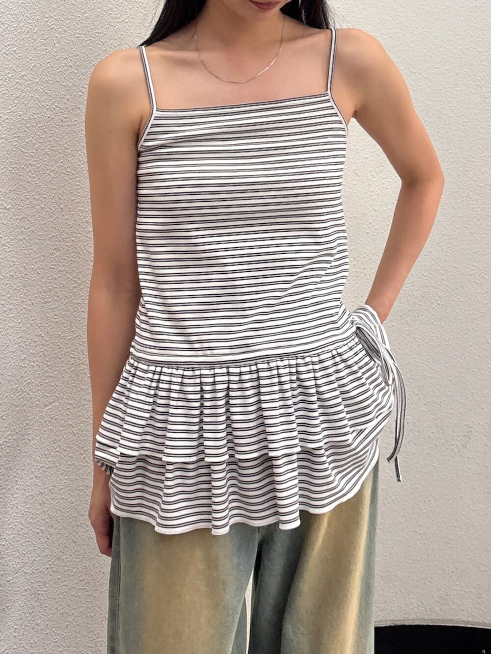 ブルー系のデニムパンツ、ブラック系のサンダル、ブラック系のハンドバッグを着用したレディースの夏コーディネートの7枚目の写真