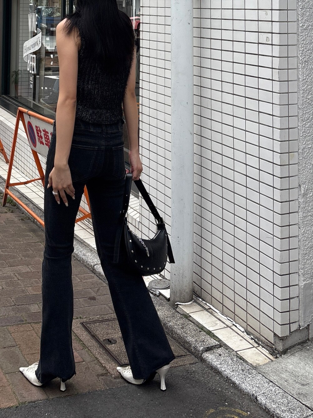 ブラック系のデニムパンツ、ブラック系のニット/セーター、ホワイト系のパンプスを着用したレディースの春コーディネートの2枚目の写真