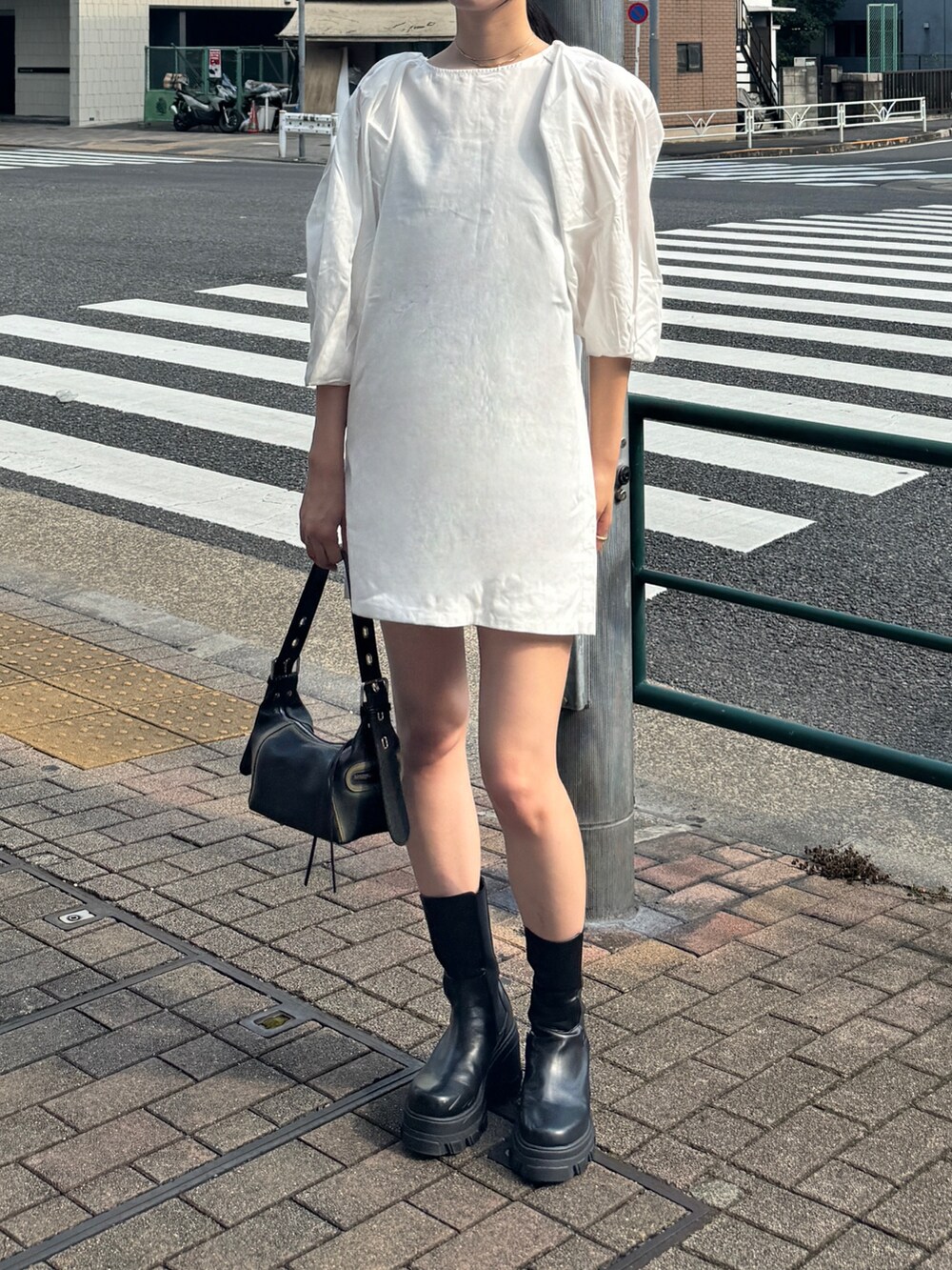 ホワイト系のワンピース、ブラック系のブーツ、ブラック系のハンドバッグを着用したレディースの夏コーディネートの2枚目の写真