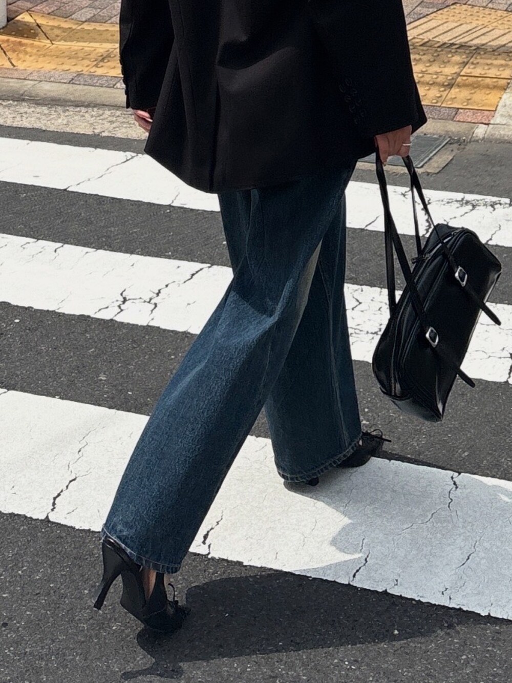 ブルー系のデニムパンツ、ブラック系のパンプス、ブラック系のニット/セーターを着用したレディースの春コーディネートの2枚目の写真