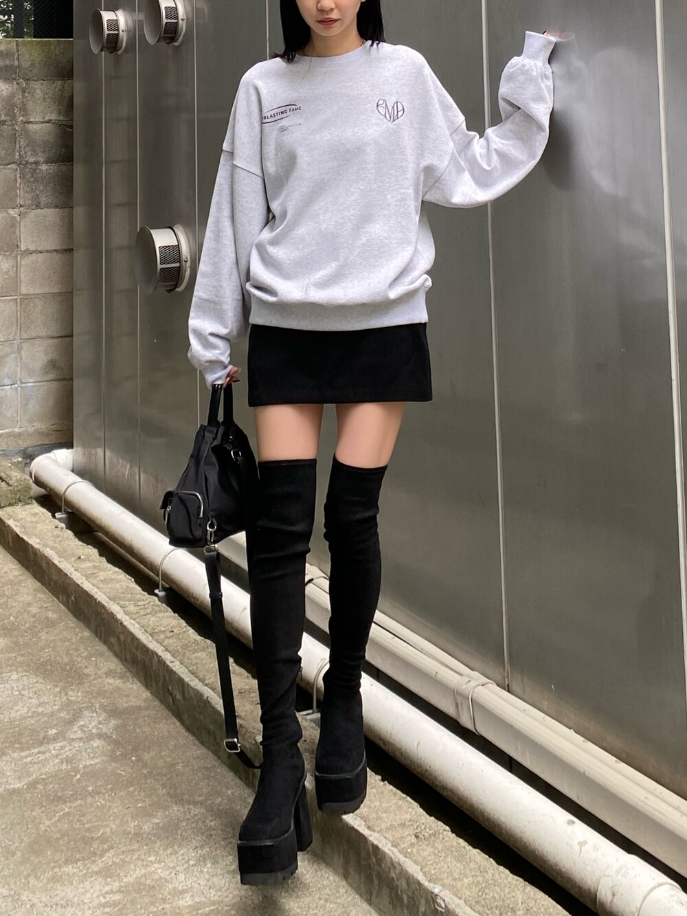 ブラック系のハンドバッグ、ブラック系のブーツ、グレー系のスウェットを着用したレディースの夏コーディネートの2枚目の写真