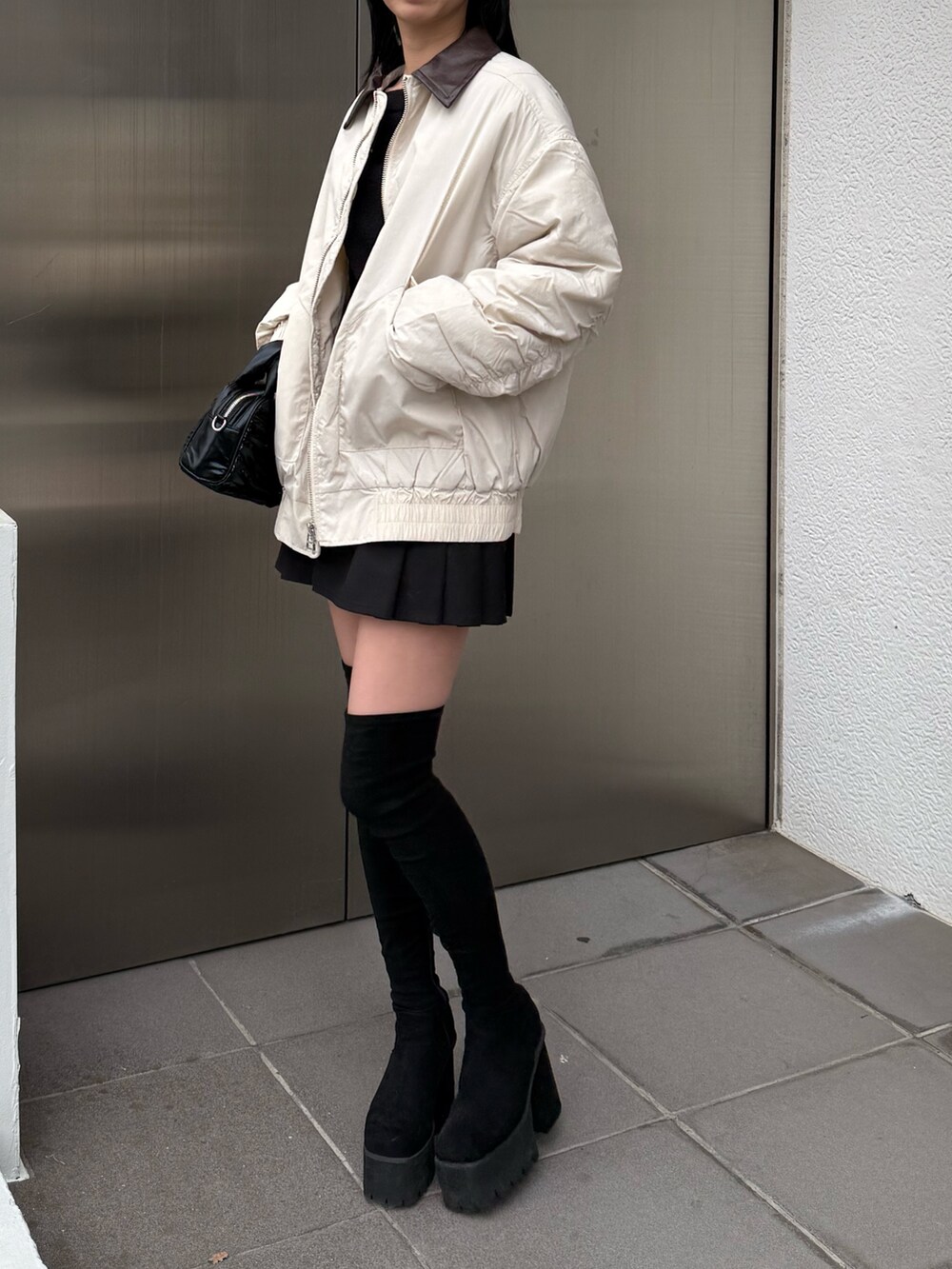 ブラック系のブーツ、ホワイト系のブルゾンを着用したレディースの冬コーディネートの2枚目の写真