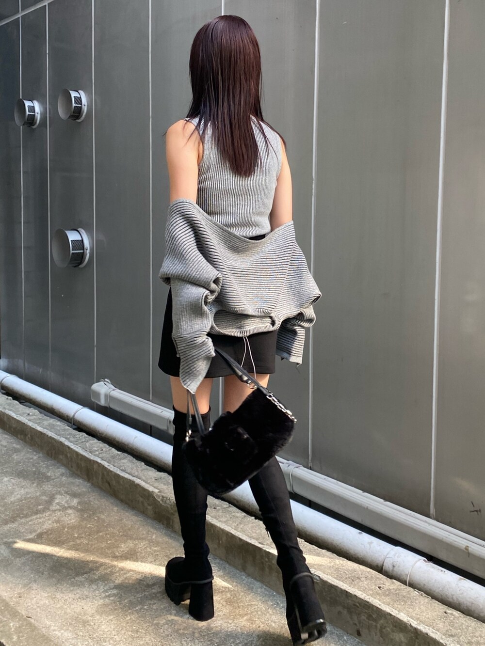 グレー系のニット/セーター、ブラック系のスカート、ブラック系のブーツを着用したレディースの夏コーディネートの2枚目の写真
