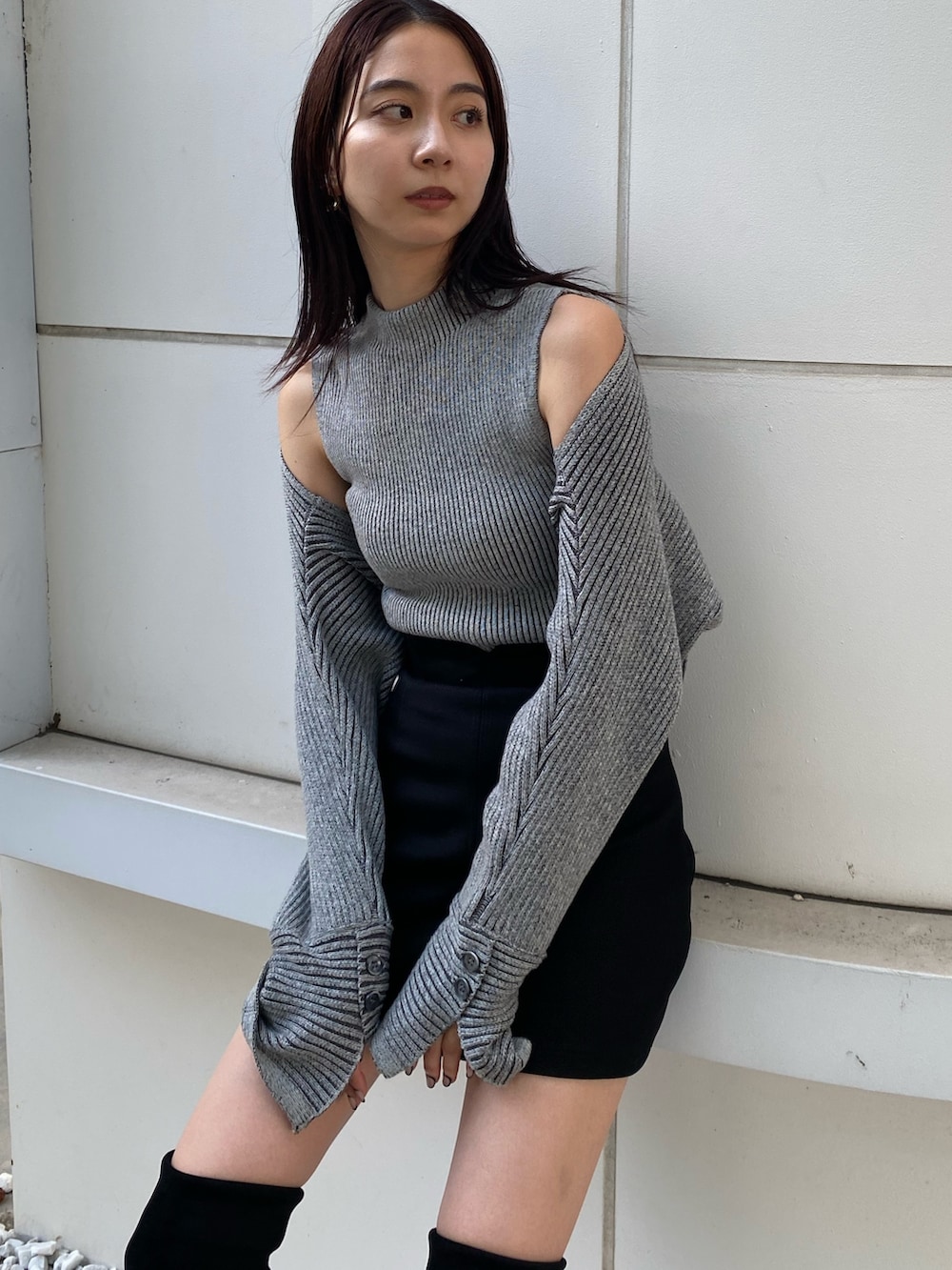 グレー系のニット/セーター、ブラック系のスカート、ブラック系のブーツを着用したレディースの夏コーディネートの4枚目の写真