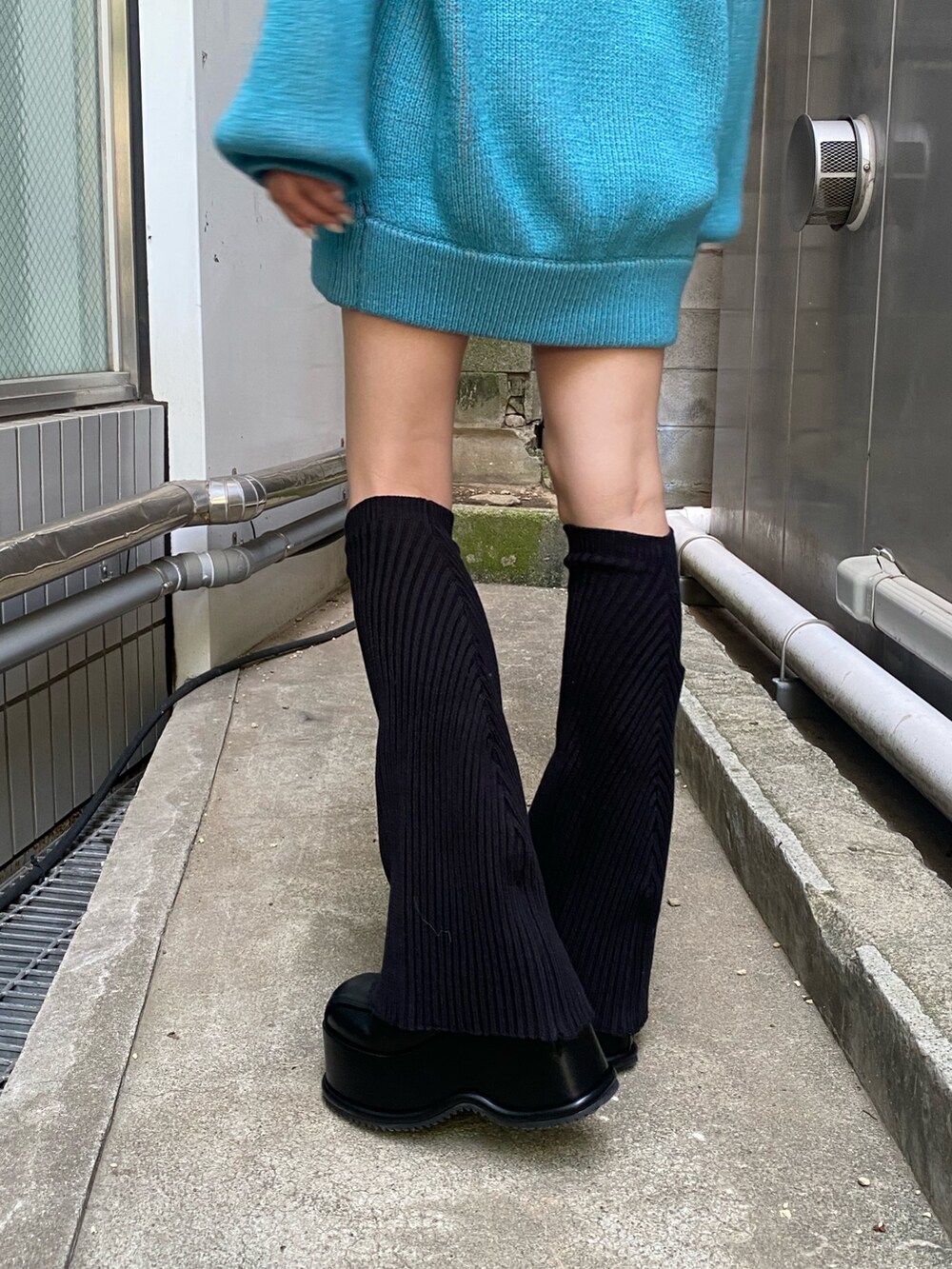 ブルー系のニット/セーター、ブラック系のローファー、ブラック系のレッグウォーマーを着用したレディースの秋コーディネートの3枚目の写真