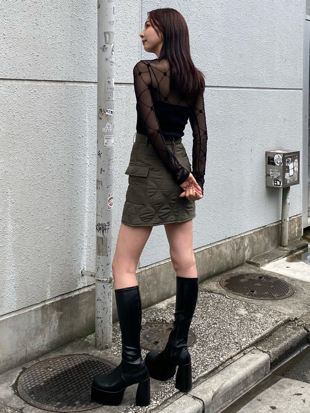 ブラック系のTシャツ/カットソー、グリーン系のスカート、ブラック系のブーツを着用したレディースの秋コーディネートの2枚目の写真