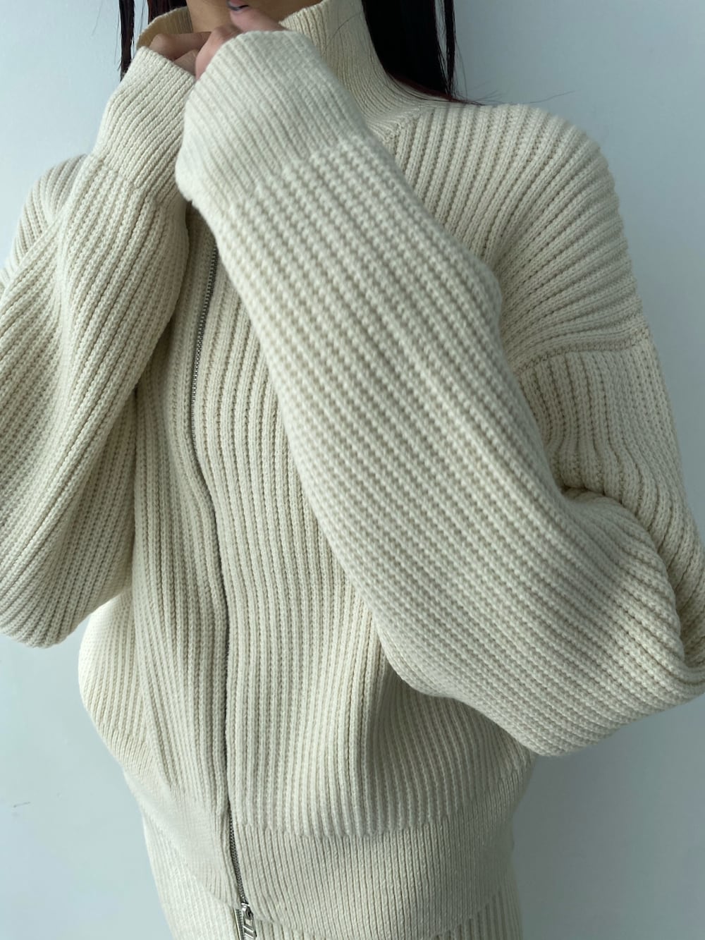 ホワイト系のニット/セーター、ホワイト系のスカート、ブラック系のブーツを着用したレディースの秋コーディネートの4枚目の写真