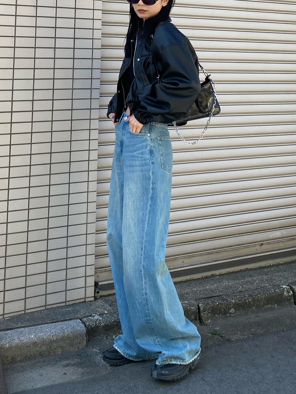 ブラック系のブルゾン、ブルー系のデニムパンツを着用したレディースの春コーディネートの4枚目の写真